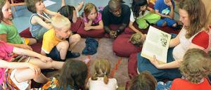 Beim Bilderbuchkino liest eine Mitarbeiterin eine Kindergeschichte vor, die mit Bildern auf einer Leinwand untermalt wird.