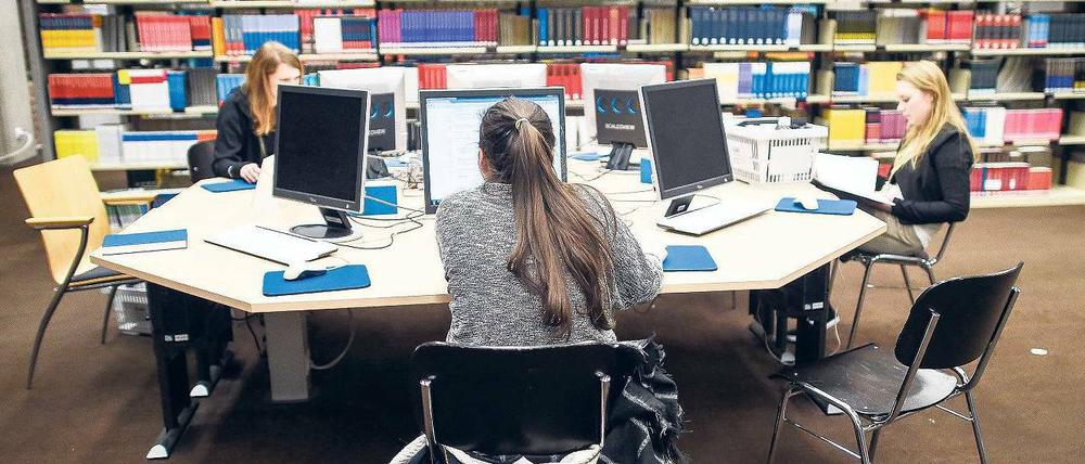 Studierende arbeiten in einer Bibliothek an Computern.