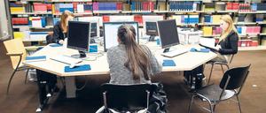 Studierende arbeiten in einer Bibliothek an Computern.