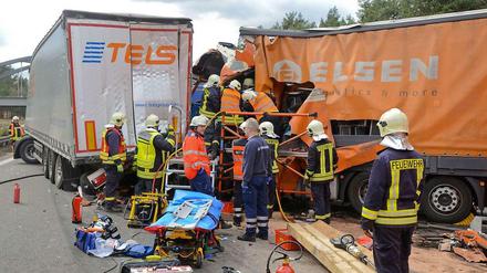Feuerwehrleute und Rettungskräfte versuchen nach einem Unfall auf dem südlichen Berliner Ring bei Michendorf (Brandenburg) einen LKW-Fahrer aus dem Fahrerhaus zu befreien. 