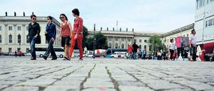 Vier junge Frauen und Männer gehen über einen Platz, in ihren Rücken ist das Hauptgebäude der Humboldt-Universität zu sehen.