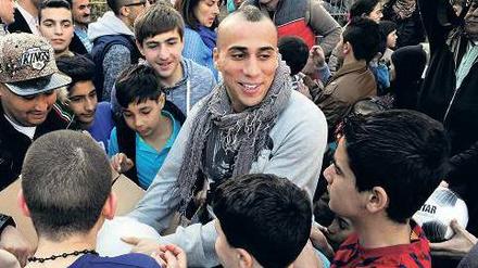 Autogramme vom Fußball-Profi. Änis Ben-Hatira spricht mit Flüchtlingskindern auf dem Bolzplatz.