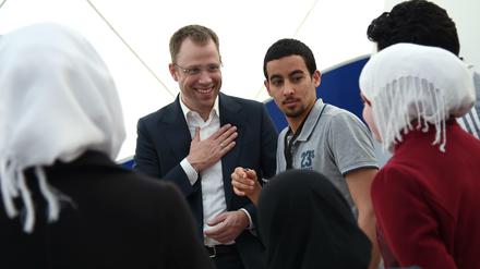 Auf Tuchfühlung. Senator Mario Czaja unterhält sich bei seinem Besuch einer Notunterkunft für Flüchtlinge am Donnerstag mit einer syrischen Familie.