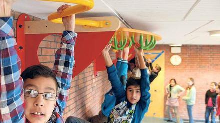 Schülern hangeln an einem Spielgerät im Schulflur.