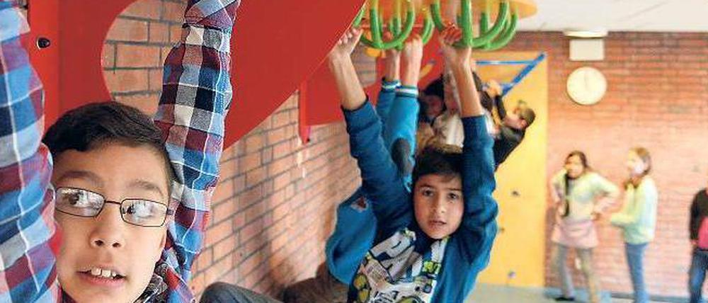 Schülern hangeln an einem Spielgerät im Schulflur.