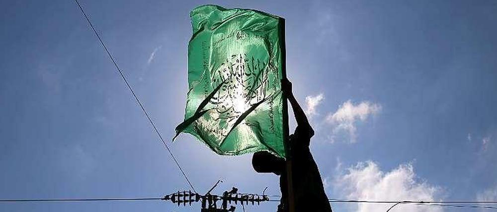 Ein militantes Mitglied des militärischen Flügels der palästinensischen Hamas hält im Gaza-Streifen eine Hamas-Fahne hoch.