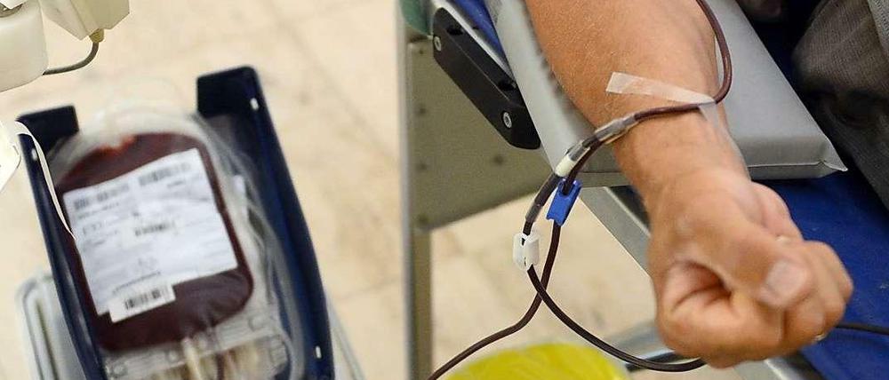 Arm eines Blutspenders mit Nadel und Blutkonserve.