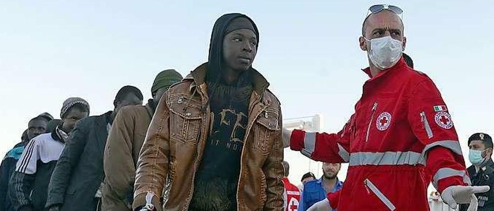 Mitarbeiter des italienischen Roten Kreuzes und gestrandete Flüchtlinge auf Sizilien. 