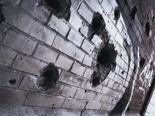 Reinhardstraße. Die Ziegelwand wurde von Sprayern übermalt, die Löcher blieben.