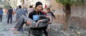 In Aleppo trägt am Sonntag, 3. Mai, ein Mann einen verletzten Jungen durch die Straßen. Eine Schule war Angaben von Aktivisten zufolge von einer Bombe des Assad-Regimes getroffen worden.