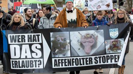 Menschen halten auf einer Demonstration Plakate mit Affenköpfen in Versuchsapparaturen und mit Aufschriften wie "Affenfolter stoppen".