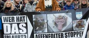 Menschen halten auf einer Demonstration Plakate mit Affenköpfen in Versuchsapparaturen und mit Aufschriften wie "Affenfolter stoppen".