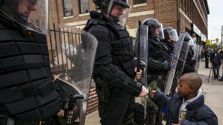Ein Junge begrüßt Polizisten in Baltimore. Der soziale Frieden ist in der Ostküstenstadt vorläufig wieder hergestellt.