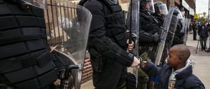 Ein Junge begrüßt Polizisten in Baltimore. Der soziale Frieden ist in der Ostküstenstadt vorläufig wieder hergestellt.