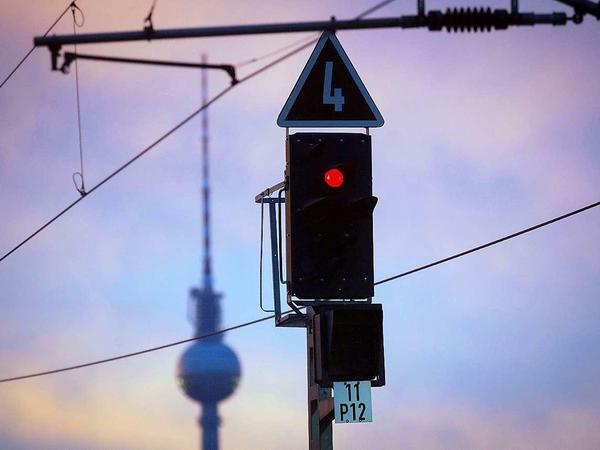 Signalleuchten stehen vor dem Hauptbahnhof in Berlin im Sonnenaufgang auf Rot.