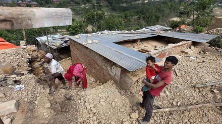 Eine Familie in Nepal an ihrem verschütteten Haus. 