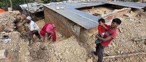 Eine Familie in Nepal an ihrem verschütteten Haus. 