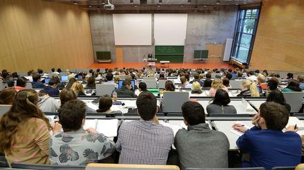 In einem Hörsaal sitzen Studierende, vorne steht ein Hochschullehrer.