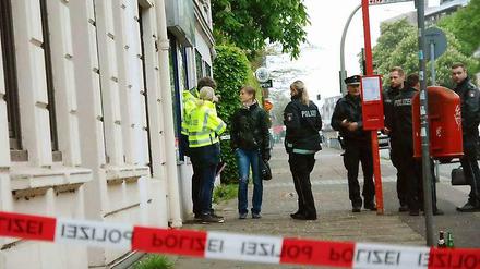 Polizeibeamte stehen am 10.05.2015 in Hamburg-Billstedt hinter einer Absperrung. Hier war in der Nacht ein 22-Jähriger niedergestochen worden, er starb noch am Tatort.