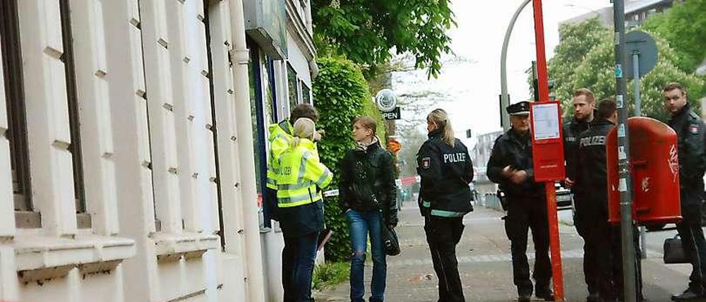 Polizeibeamte stehen am 10.05.2015 in Hamburg-Billstedt hinter einer Absperrung. Hier war in der Nacht ein 22-Jähriger niedergestochen worden, er starb noch am Tatort.