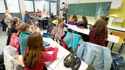 Ein Lehrer steht gestikulierend vor einer Schulklasse.