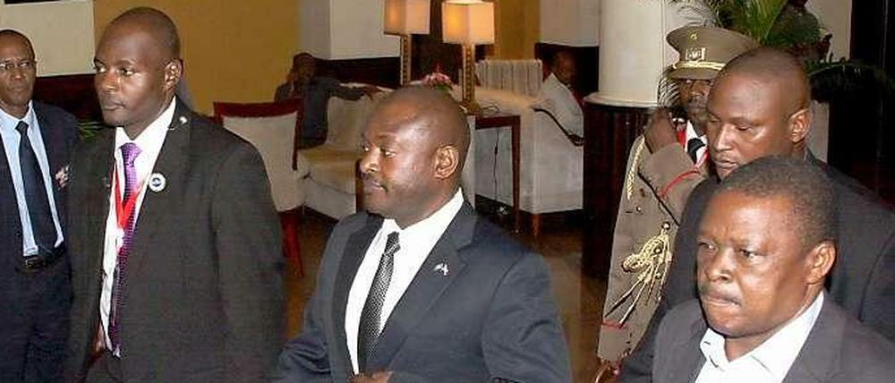 Burundis Präsident Pierre Nkurunziza wird von seinen Sicherheitsleuten aus einem Hotel in der tansanischen Hafenstadt Daressalam geführt. Er machte sich dann auf dem Landweg auf zurück in sein Heimatland.