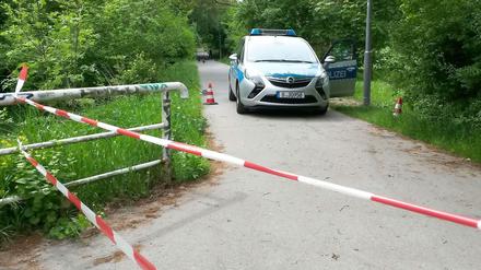 Ein Polizeiauto am Tatort in Kaulsdorf. Die Stelle auf dem Verbindungsweg zwischen Bahnhof Wuhletal und Wohnsiedlung ist mit Flatterband abgesperrt.