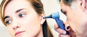 Ohrenarzt schaut einer Frau ins Ohr. 