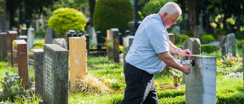 Friedhofsaufseher Reiner Dölfel testet auf dem Pragfriedhof in Stuttgart die Standfestigkeit eines Grabsteins. Auf dem Friedhof müssen Jährlich über 13000 Gräber überprüft werden.