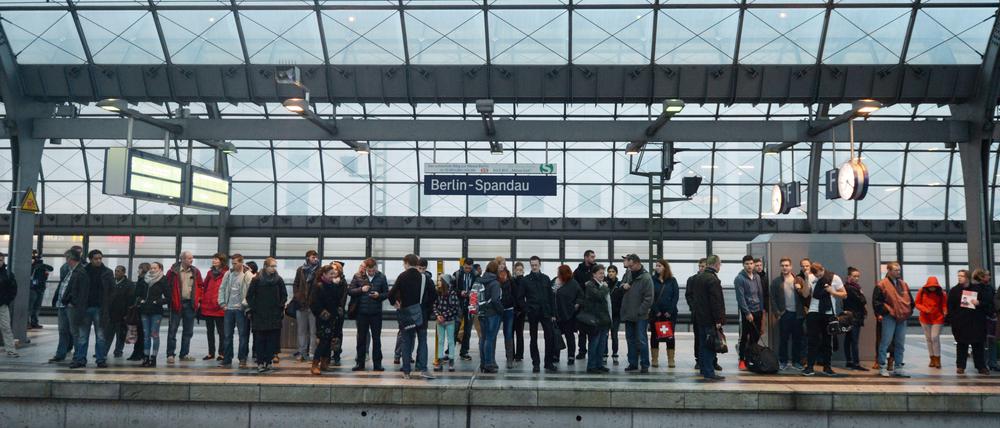 Fahrgäste warten auf einem Bahnsteig des Bahnhofs in Berlin-Spandau auf einen Zug.