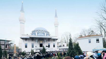 Vor einer Moschee stehen Menschen.