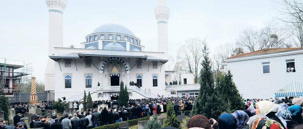 Vor einer Moschee stehen Menschen.