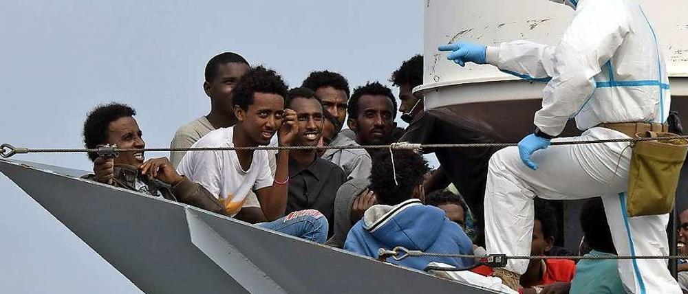 Diese Flüchtlinge haben Glück gehabt. Ein Militärschiff hat sie rechtzeitig aus dem Mittelmeer gezogen. Nun warten Sie darauf, in Italien an Land zu gehen.