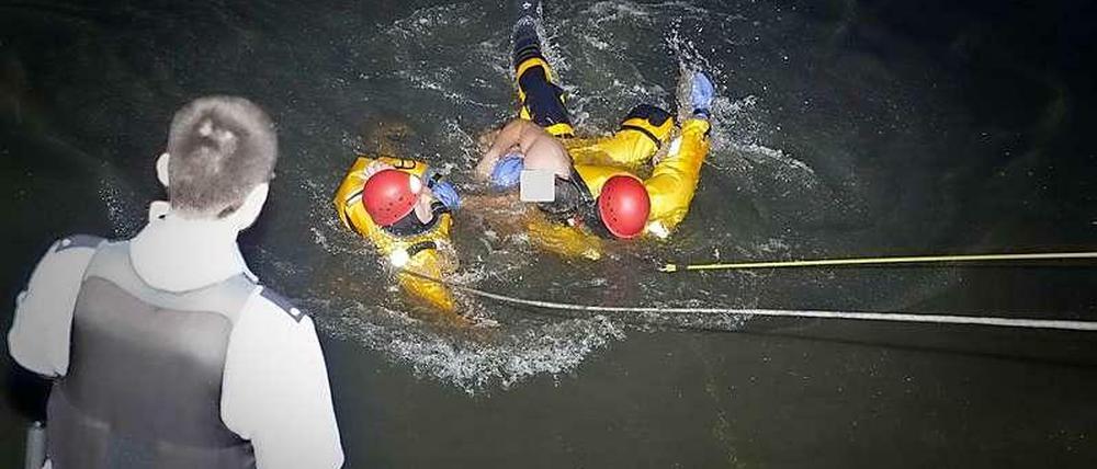 Zwei Feuerwehrleute holen den Schwimmer aus dem Wasser.