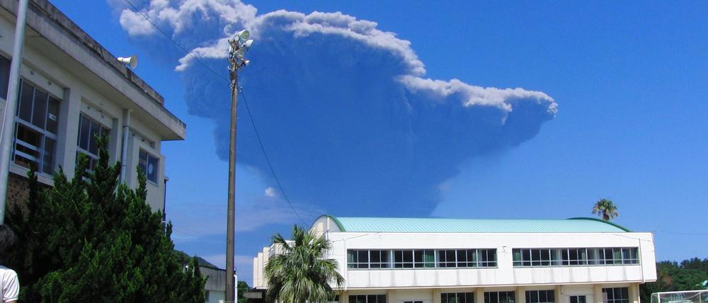Schulkinder betrachten die Rauchentwicklung am Himmel. Im Südwesten von Japan ist der Vulkan Shindake ausgebrochen. Mehr als neun Kilometer türmten sich die dicken schwarzen Aschewolken über dem Krater auf der Insel Kuchinoerabu in den Himmel.