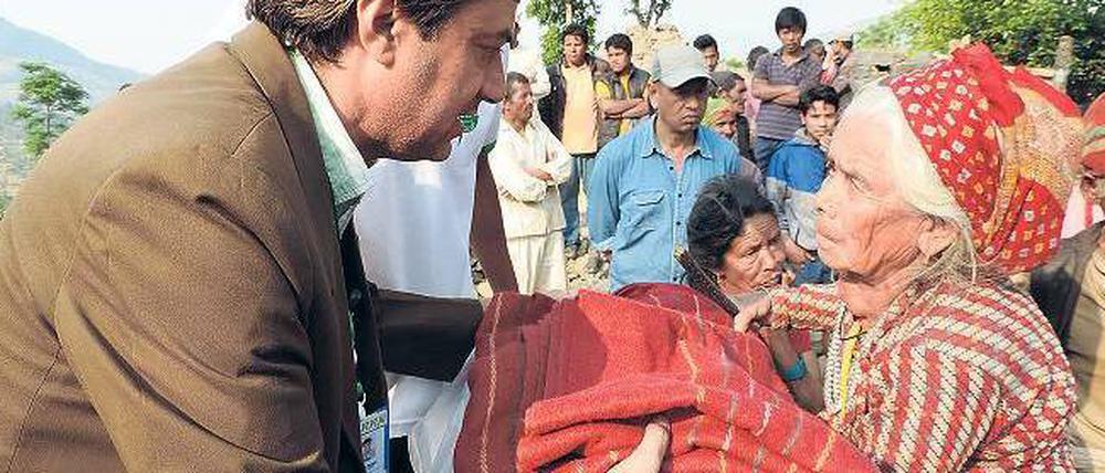 Für sie. Ein Helfer einer lokalen Partnerorganisation der Deutschen Welthungerhilfe (DWHH) übergibt einer alten Frau an einer Ausgabestelle nahe Kathmandu eine Decke.