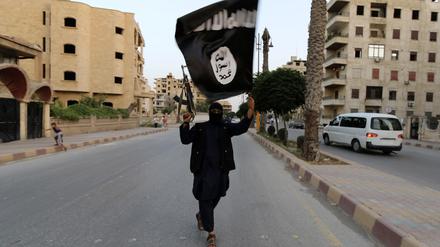 A member loyal to the Islamic State in Iraq and the Levant (ISIL) waves an ISIL flag in Raqqa June 29, 2014. The offshoot of al Qaeda which has captured swathes of territory in Iraq and Syria has declared itself an Islamic "Caliphate" and called on factions worldwide to pledge their allegiance, a statement posted on jihadist websites said on Sunday. The group, previously known as the Islamic State in Iraq and the Levant (ISIL), also known as ISIS, has renamed itself "Islamic State" and proclaimed its leader Abu Bakr al-Baghadi as "Caliph" - the head of the state, the statement said. REUTERS/Stringer (SYRIA - Tags: POLITICS CIVIL UNREST TPX IMAGES OF THE DAY) FOR BEST QUALITY IMAGE ALSO SEE: GF2EAAO0VU501 - RTR3WBPT