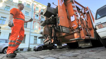 Berliner Stadtreinigung im Einsatz, BSR-Mann in Orange am Müllwagen.