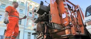 Berliner Stadtreinigung im Einsatz, BSR-Mann in Orange am Müllwagen.