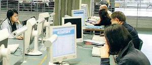 In einer Unibibliothek sitzen Studierende an Computern.