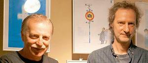 Einladung zur Karikaturenschau. Die Wettbewerbsveranstalter Valeriu Kurtu (li.) und Paul Gross mit dem Sieger-Cartoon.von Sergey Semendyaev.