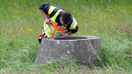 Ein Polizist schaut am Mittwoch bei einem Waldstück in Wilhelmsdorf bei Stendal (Sachsen-Anhalt) in eine Betongrube. Im Fall der vermissten Inga aus Schönebeck durchsucht die Polizei erneut ein Waldstück.