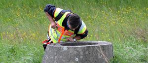 Ein Polizist schaut am Mittwoch bei einem Waldstück in Wilhelmsdorf bei Stendal (Sachsen-Anhalt) in eine Betongrube. Im Fall der vermissten Inga aus Schönebeck durchsucht die Polizei erneut ein Waldstück.