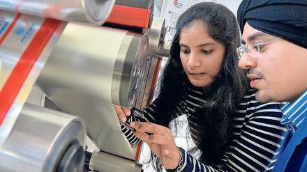 Eine junge Frau und ein junger Mann arbeiten an einer Druckmaschine.