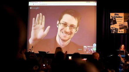 Edward Snowden ist auf einer Videoleinwand zu sehen, er wirkt dem Publikum im Saal zurück.