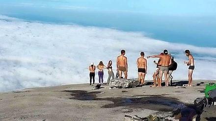 Die Gruppe von Touristen auf einem Berg Kinabala in Malaysia. Die Touristen entblößen sich. Wenige Tage später erschüttert ein Erdbeben das Land.