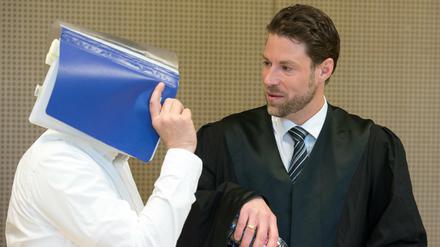 Der Angeklagte Mario K. verdeckt mit einem Hefter sein Gesicht neben seinem Anwalt Christian Lödden vor Beginn des wohl vorletzten Verhandlungstages am Montag am Landgericht in Frankfurt (Oder).