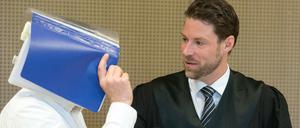 Der Angeklagte Mario K. verdeckt mit einem Hefter sein Gesicht neben seinem Anwalt Christian Lödden vor Beginn des wohl vorletzten Verhandlungstages am Montag am Landgericht in Frankfurt (Oder).