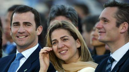 König Felipe von Spanien (l) sitzt im Jahre 2003 neben seiner Schwester Cristina und deren Mann Inaki Urdangarin. Aufgrund einer Finanzaffäre wurde Cristina der Fürstentitel aberkannt.