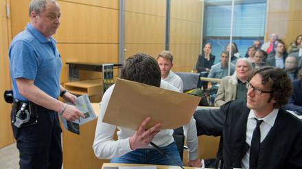 Der Angeklagte Sanel M. wird am 24.04.2015 zu Verhandlungsbeginn in einen Sicherheitssaal des Landgerichts in Darmstadt geführt und nimmt neben seinem Anwalt Stephan Kuhn (r) Platz.